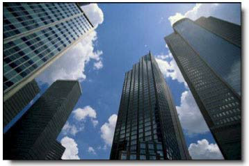 Upward view of towering skyscrapers reaching towards a light blue sky dotted with clouds